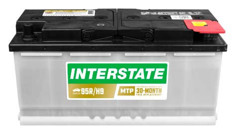 Long car battery, white case with black top. Recessed termianls, Interstate label.