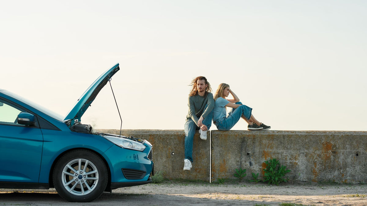 couple leaning against each other with car / hood open